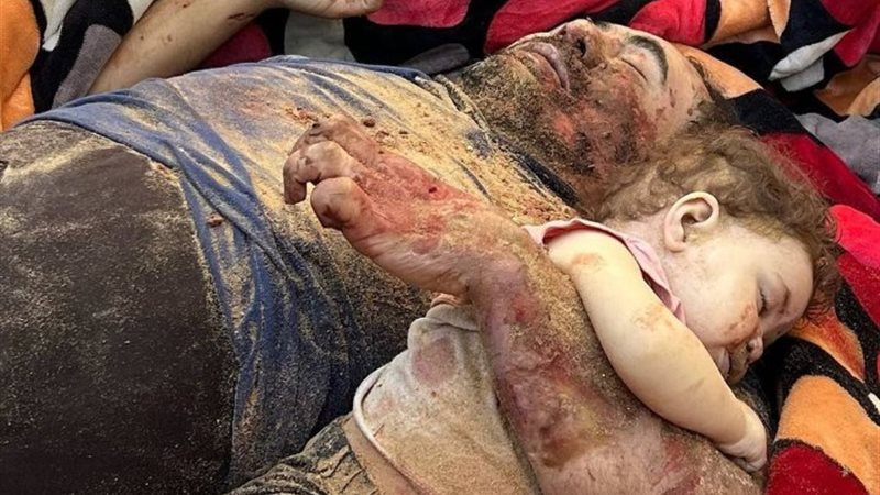 أب يحتضن طفلته الصغيرة خوفاً من القصف العدواني