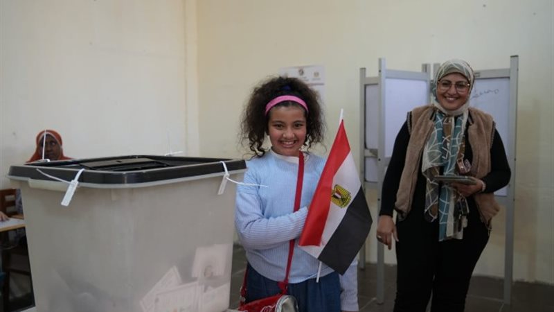طفلة تشارك والدتها أثناء الإدلاء بصوتها